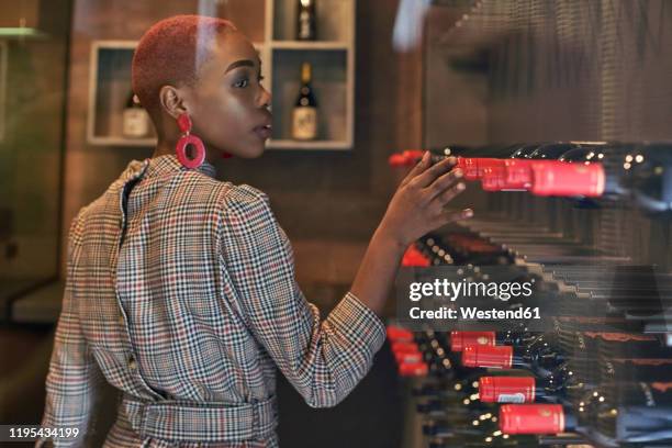 young woman with short haircut choosing a wine in her cellar - vinger bildbanksfoton och bilder