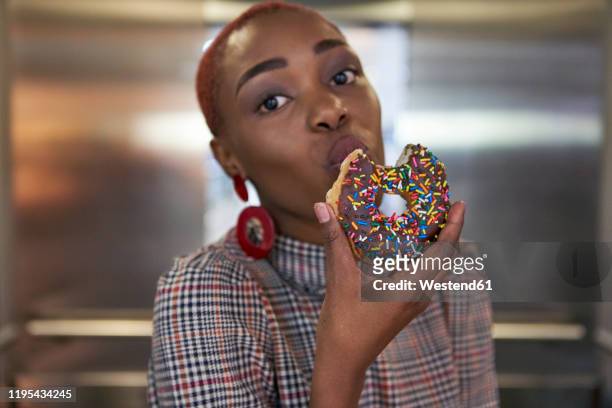 young woman eating a doughnut in an elevator - biting donut stock pictures, royalty-free photos & images