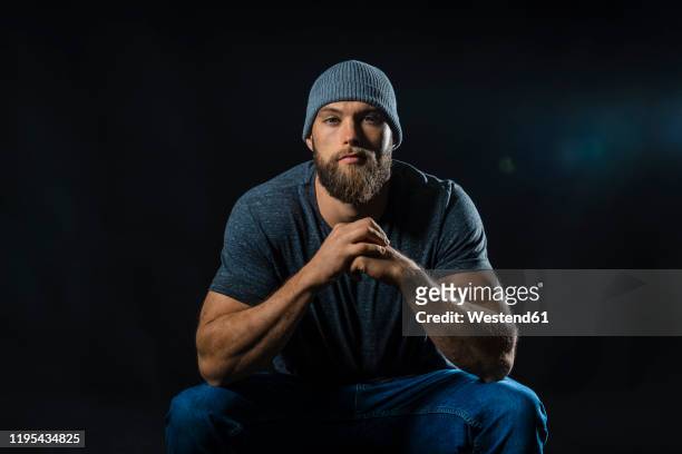 portrait of a muscular man sitting in studio - heroic style stock pictures, royalty-free photos & images
