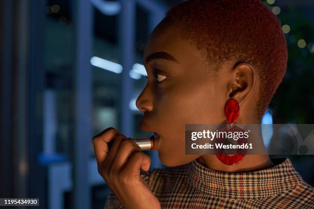 portrait of young woman with short hair applying lipstick - earring stock pictures, royalty-free photos & images