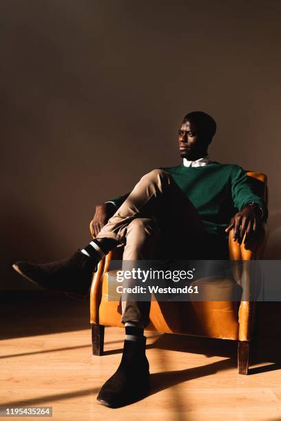 man sitting in leather armchair looking sideways - man office chair stock pictures, royalty-free photos & images