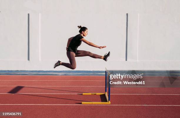 female hurdler during training on tartan track - leichtathletik stock-fotos und bilder