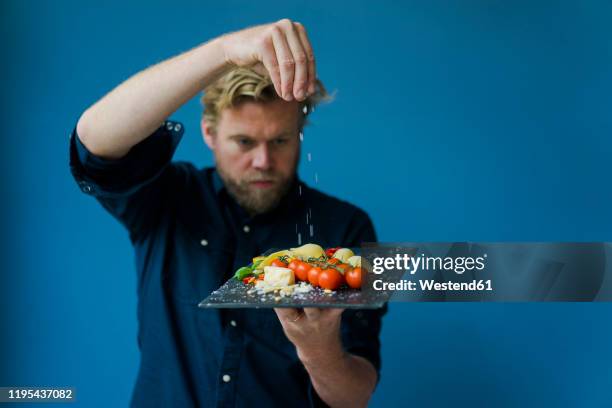 man seasoning platter with cheese and tomatoes - strooisels stockfoto's en -beelden