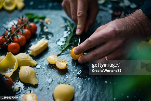 hand chopping tomatoes on platter with pasta and herbs - イエロートマト ストックフォトと画像