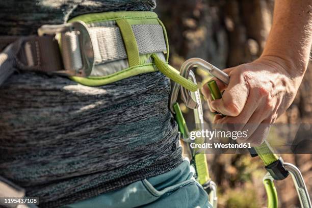 woman preparing to climb, putting on climbing harness - messa in sicurezza foto e immagini stock