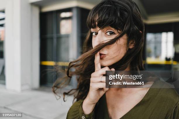 portrait of smiling brunette woman, finger on mouth - silence 個照片及圖片檔