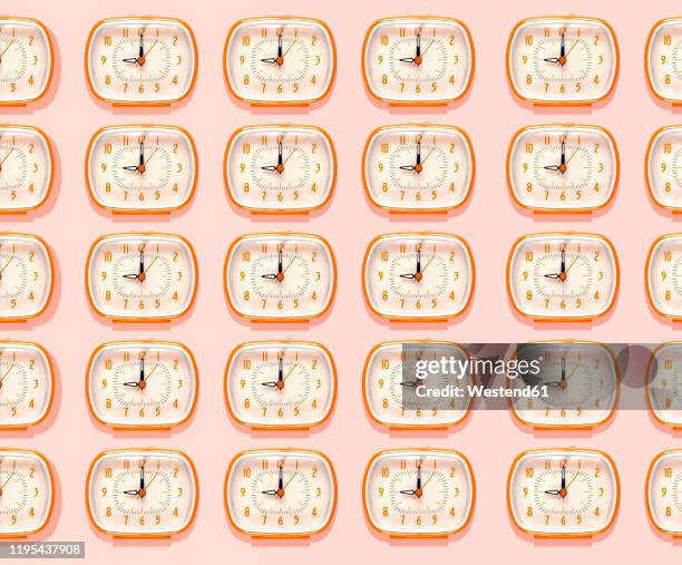 3d illustration, row of orange alarm clocks at nine o'clock pattern on pink background - orange alarm clock stock pictures, royalty-free photos & images