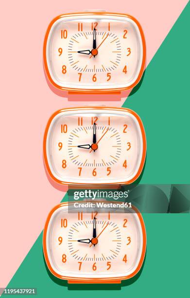 3d illustration, row of orange alarm clocks at nine o'clock on pink and mint green background - orange alarm clock stock pictures, royalty-free photos & images