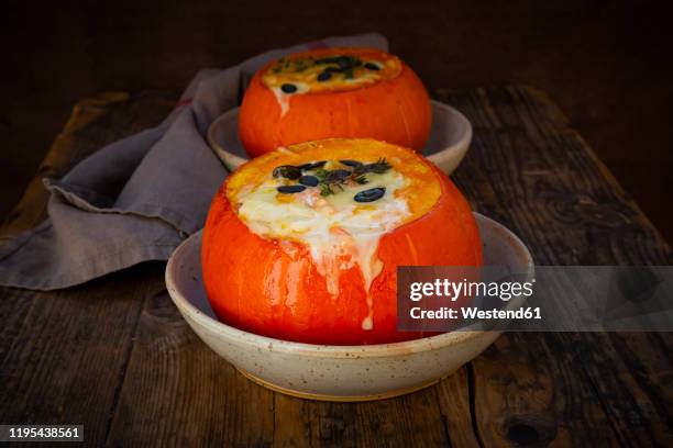 two hokkaido squashes stuffed with camembert cheese, thyme and pumpkin seeds - plein photos et images de collection