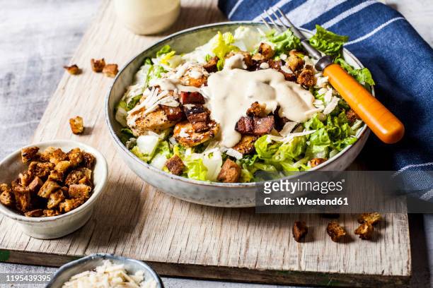 bowl of caesar salad with romaine lettuce, parmesan†cheese, bacon, chicken breast and croutons - cheese salad stock-fotos und bilder