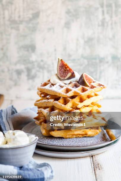 plate of thick belgian†waffles with whipped cream, powdered sugar and figs - belgium waffles stock pictures, royalty-free photos & images