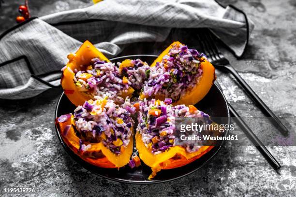 quartered hokkaido squash filled with†rice, red cabbage, paprika, broccoli, onions and carrots - quarter foto e immagini stock