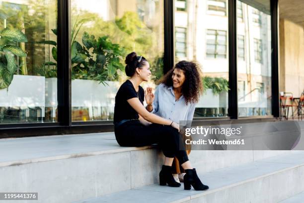 two friends sitting on steps, gossipping - man stairs sitting stock-fotos und bilder