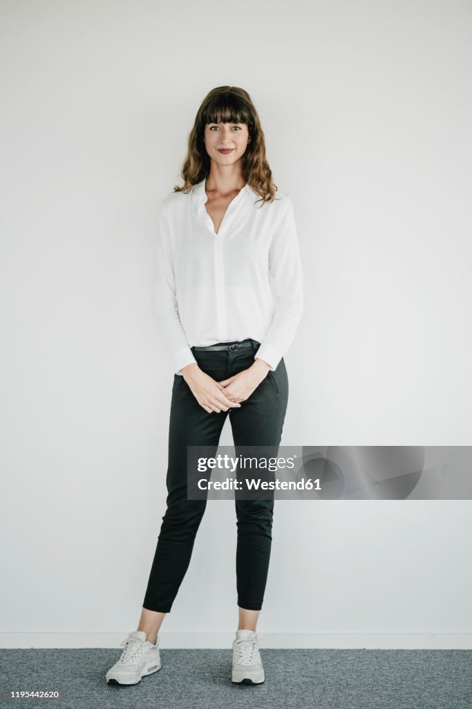 Smiling businesswoman standing in front of a white wall