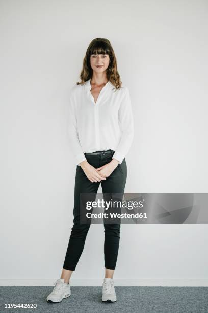 smiling businesswoman standing in front of a white wall - de pé imagens e fotografias de stock