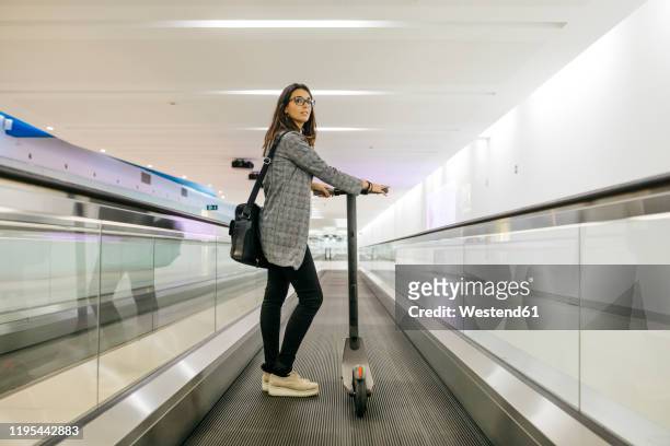 businesswoman with her electric scooter on moving walkway - mobility scooter photos et images de collection