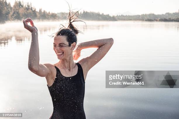 cheerful woman wearing black swimsuit at a lake at morning mist - river bathing stock pictures, royalty-free photos & images