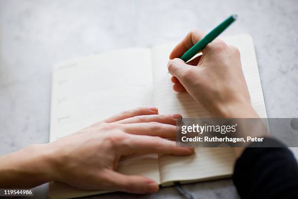 woman writing on diary - contact list stockfoto's en -beelden