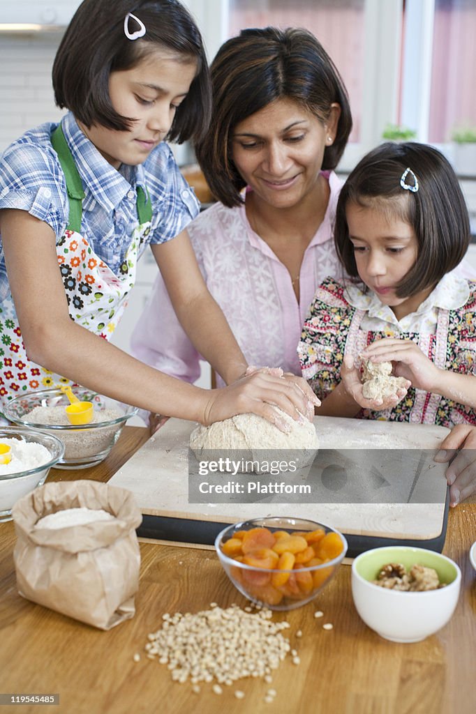 Mother baking with girls in kitchen