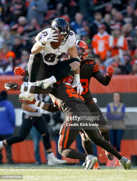 Mark Andrews of the Baltimore Ravens jumps over Damarious Randall of the Cleveland Browns during first half in the game at FirstEnergy Stadium on...