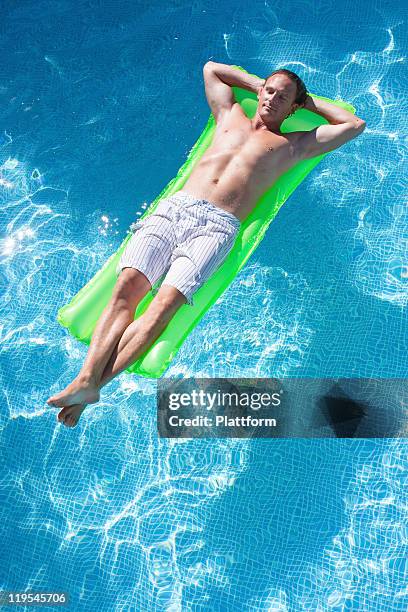 man on inflatable raft in swimming pool - man on float stock pictures, royalty-free photos & images