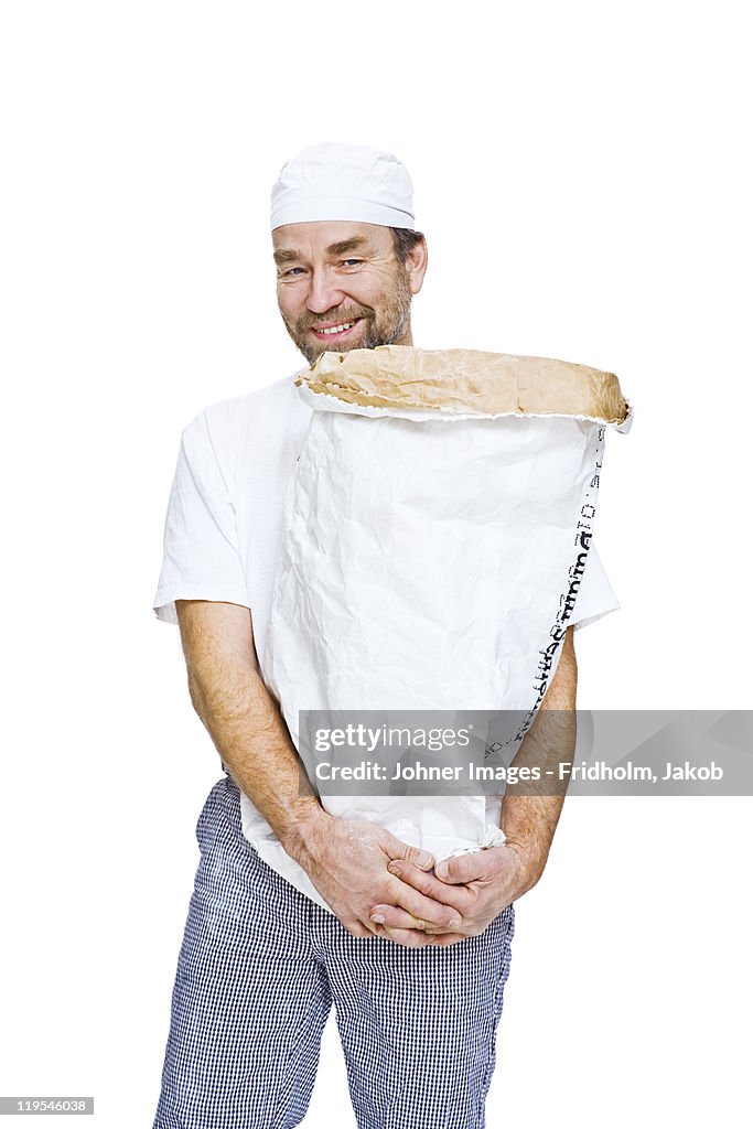 Studio portrait of male baker holding sack
