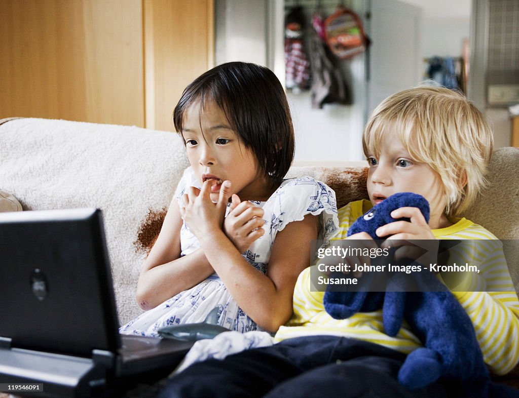 Boy and girl watching tv on sofa