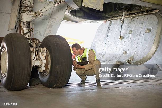 aircraft worker checking airplane - landing gear stock-fotos und bilder