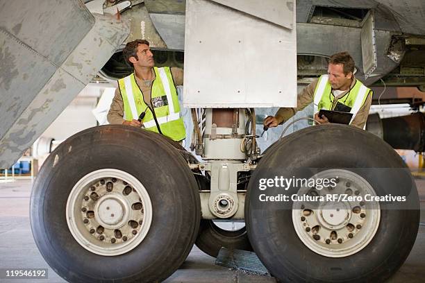 aircraft workers checking airplane - landing gear stock-fotos und bilder