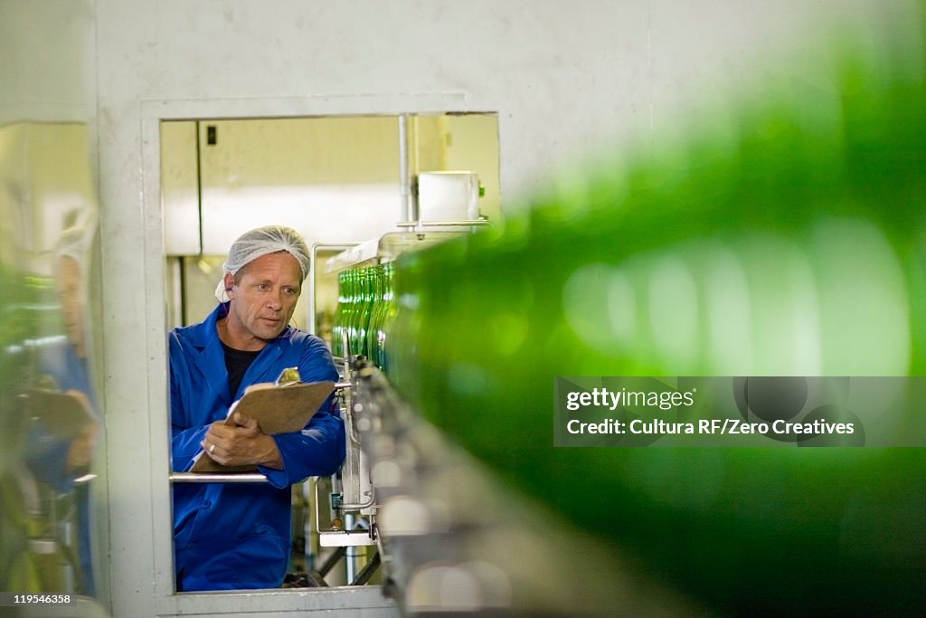 Worker examining bottles in factory