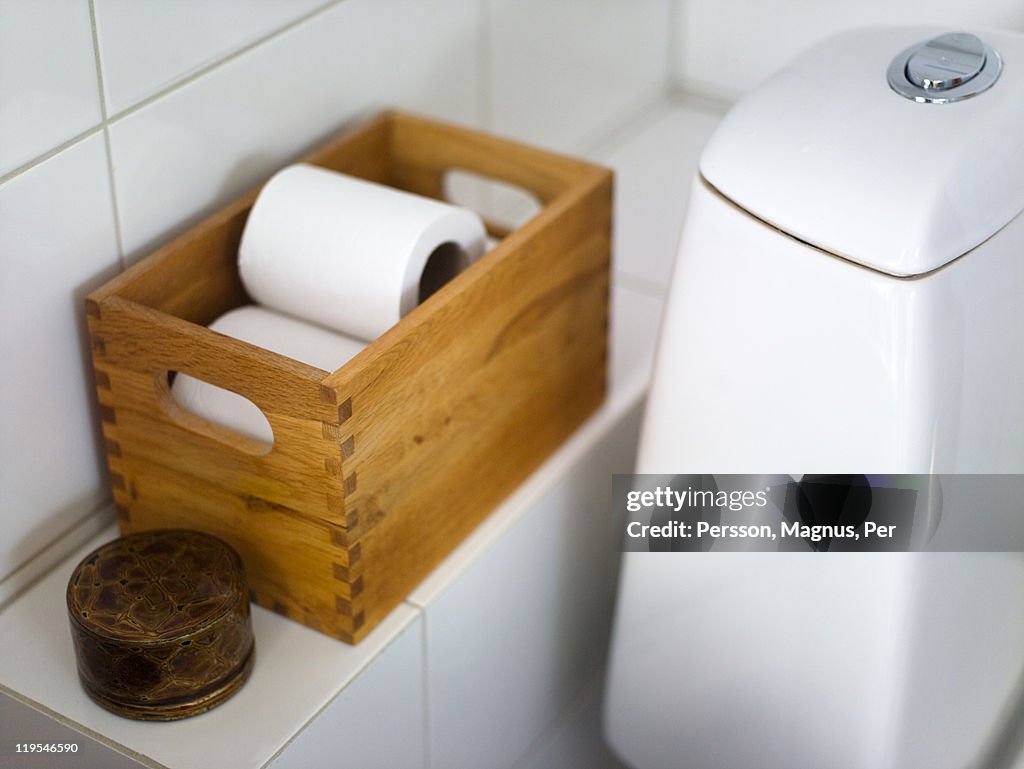 Toilet paper in crate on bathroom shelf