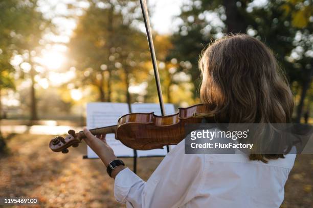 langharige kind het spelen van een viool buitenshuis - muziekstandaard stockfoto's en -beelden