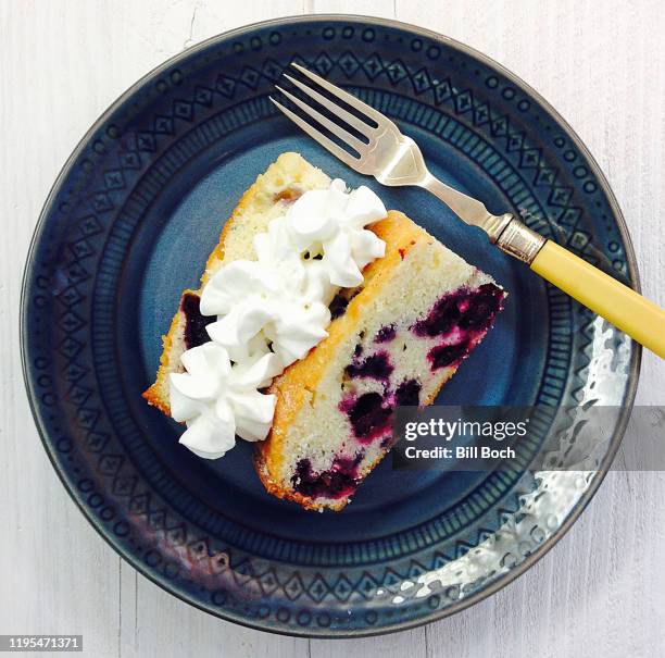 blueberry cake - 2 slices with whipped cream on top in  a blue plate  with a antique fork - whip cream cake fotografías e imágenes de stock