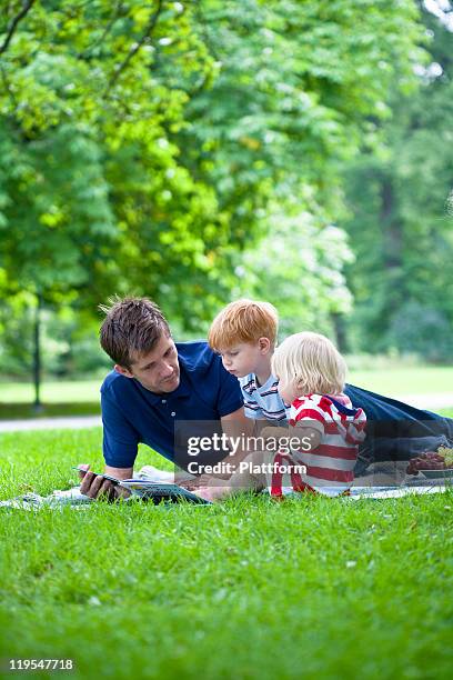 mid adult father reading  book to children - fille lire gazon photos et images de collection