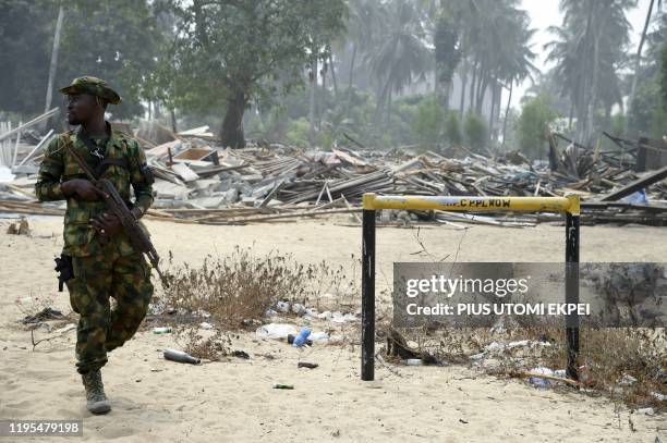 Nigerian naval personnel walks past a 'Right of Way' oil pipeline sign erected by the Nigerian National Petroleum Company and vandalised by oil...