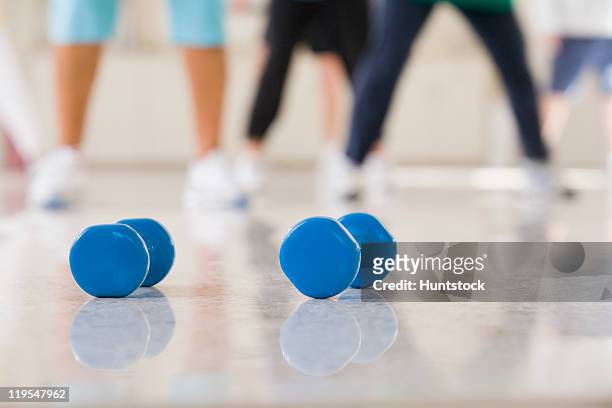 close-up of dumbbells with seniors exercising in the background - 80 year old women stock pictures, royalty-free photos & images