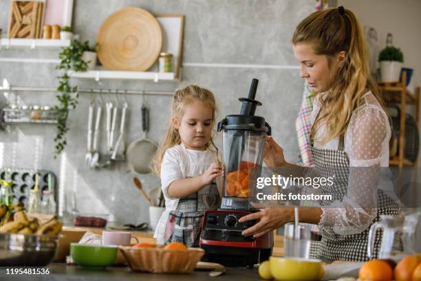 woman closing the blender after adding the freshly cut persimmons - liquidiser stock pictures, royalty-free photos & images