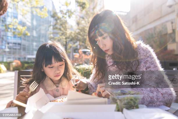 moeder en kleine dochter eten lunch op terras - asian family cafe stockfoto's en -beelden