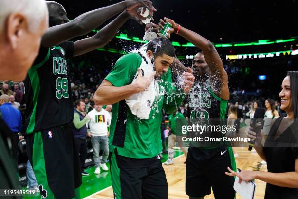 Tacko Fall and Javonte Green of the Boston Celtics give Jayson Tatum of the Boston Celtics a Gatorade-shower after the game against the Charlotte...