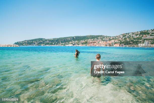 sibling having fun at beach with clear water in nice,france - nizza stock-fotos und bilder