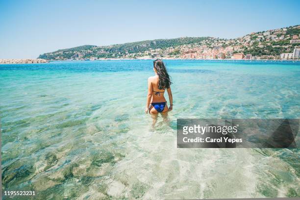 rear view young female in clear turqoise water in nice,france - nizza stock-fotos und bilder