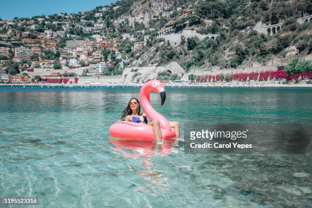 happy girl on flamingo floating on clear water in nice,france - sea water bird fotografías e imágenes de stock