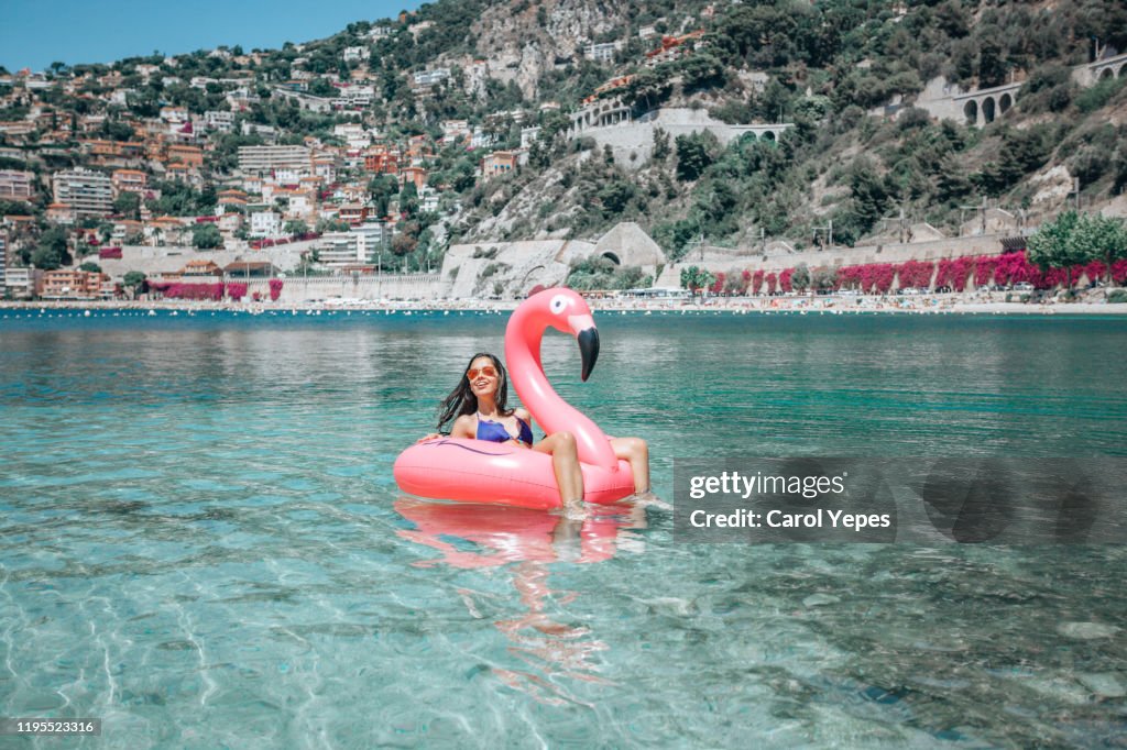 Happy girl on flamingo floating on clear water in Nice,France