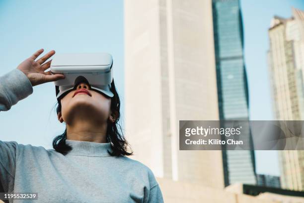 woman using virtual reality headset in the cityscape - china games day 1 fotografías e imágenes de stock