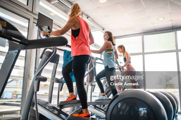 drei weibliche workout-freunde mit elliptischen trainern - cross trainer stock-fotos und bilder