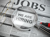 We are hiring. Job search and employment concept. Magnified glass with jobs classified ads in newspaper,
