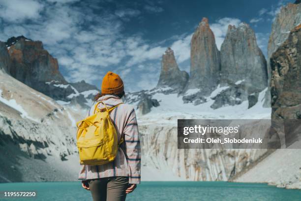 donna con zaino giallo che guarda la vista panoramica del parco nazionale torres del paine - torres del paine foto e immagini stock