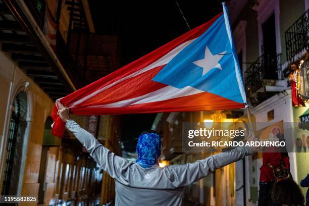 Protester holds a Puerto Rican flag during a demonstration against Puerto Rico's governor and the government in front of the governor's mansion in...