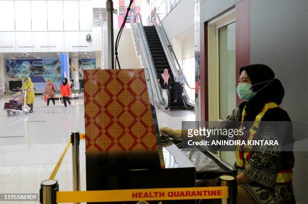 An Indonesian health officer screens passengers with a thermal scanner at the Depati Amir airport in Pangkal Pinang on Bangka Belitung island on...