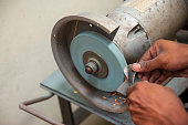 The skill operator use hand for regrinding the drill tool with the abrasive wheel.